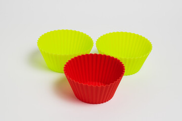 Yellow and red silicone molds for baking a cupcake on a white background