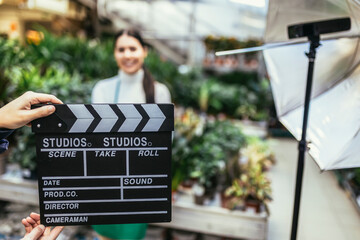Hands holding movie clapper. Photo of interview or broadcast, woman owner in her flower shop.