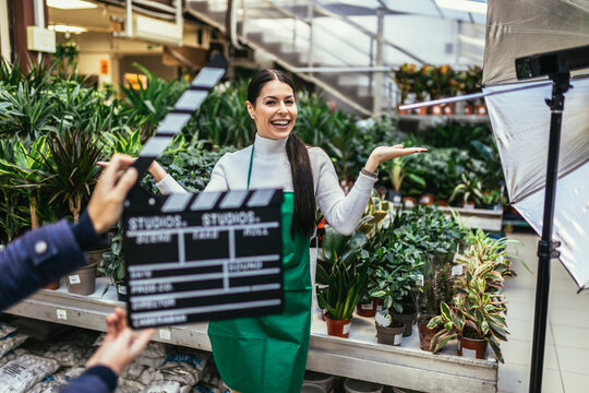 Hands holding movie clapper. Photo of interview or broadcast, woman owner in her flower shop.