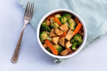 Food healthy stir fried chicken add broccoli carrot in bowl on wood table.