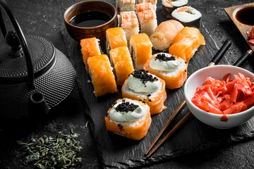 Sushi rolls with salmon and shrimp on a stone stand.