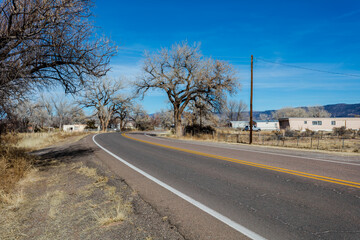 Bending roadway passing through small village in rural New Mexico on clear day