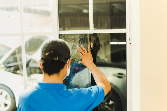 Woker wrapping tinting a house window with tinted foil.