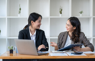 Fototapeta premium Business idea creative brainstorming sessions for projects Strategic topic of two Asian girls working together data analysis Happy clarification of various financial information at the desk.