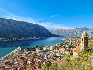 Naklejka na ściany i meble Panoramic view from Kotor city walls on Church of Our Lady of Remedy and Kotor bay in sunny summer, Adriatic Mediterranean Sea, Montenegro, Balkan Peninsula, Europe. Fjord winding along coastal towns