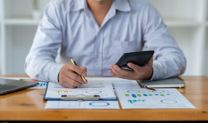 Asian businessman analyzing and brainstorming using calculators. Hand-pointing financial data on the sheet. Graph Chart showing earnings. growth teamwork process concept.