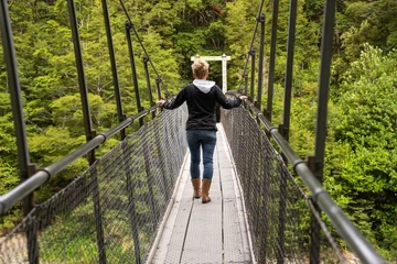 Foto op Plexiglas Woman crossing Suspension Bridge over the Blue Pools and the Makarora River, Haast Pass, West Coast, South island, New Zealand © eugenedev