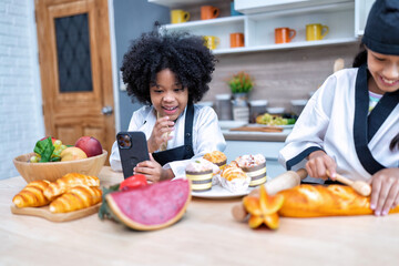 Children in learning kitchen room use mobile phone video call learn sell bread on line