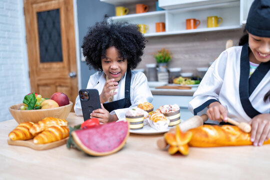 Children in learning kitchen room use mobile phone video call learn sell bread on line