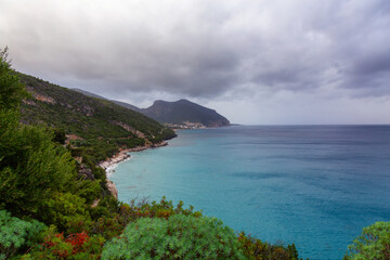 Fototapeta premium Coastline on a rocky shore near Cala Gonone, Sardinia. Cloudy Sunrise Sky.