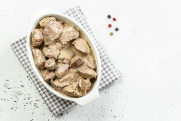 Creamy chicken liver, cream sauce in ceramic dish. Top view, copy space, flat lay.