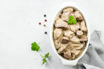 Sauteed chicken liver, cream sauce in ceramic dish. Top view, copy space, flat lay.