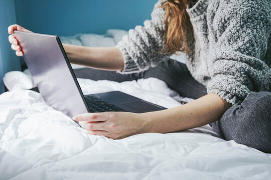 Anonymous female freelancer using computer on bed