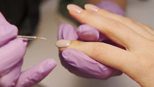 Close up video of nail master applying gel on nails at salon.