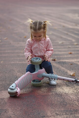 Child girl playing with a kids scooter