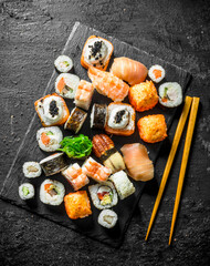 Delicious rolls, sushi and maki on a stone Board with chopsticks.