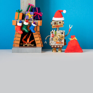 Robot Santa Claus and toy fireplace chimney. Christmas stockings, New Year gifts holiday boxes. Festive card, blue gray background. Copy space for text