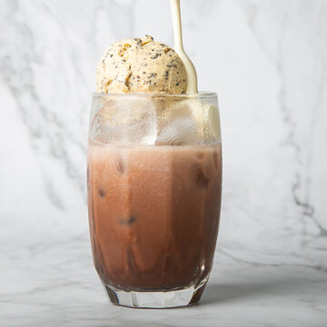 Pour the almond milk cream. Iced cocoa with vanilla ice cream in clear glass on marble Copy space for your text. square image