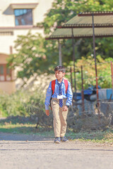 An Indian or asian little boy running on the road. Coming or going to school from home. Smiling kid.