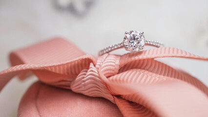 Close up of diamond ring on pink ribbon and white background. Love, valentine, relationship and...