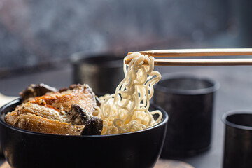 Noodles with eringi mushrooms in a black plate