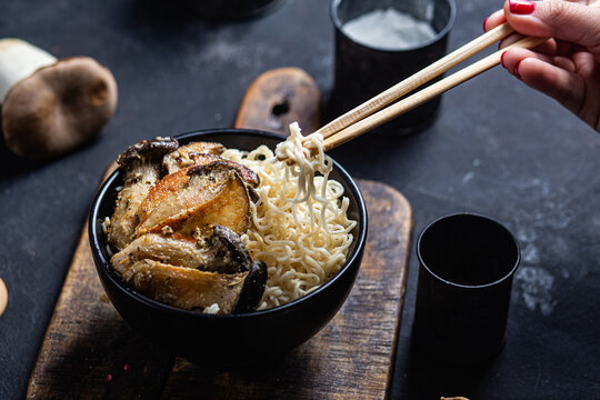Noodles with eringi mushrooms in a black plate