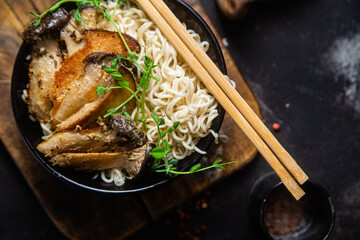 Noodles with eringi mushrooms in a black plate