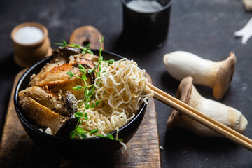 Noodles with eringi mushrooms in a black plate