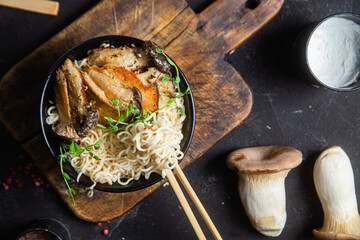 Noodles with eringi mushrooms in a black plate