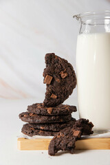Delicious and beautiful chocolate cookies stand on a wooden stand with a carafe of milk
