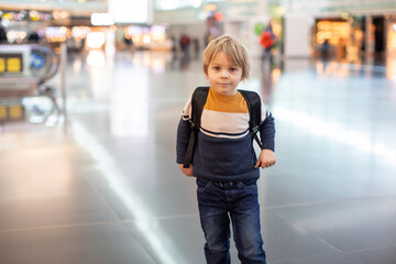 Cute  baby boy waiting boarding to flight in airport transit hall near departure gate. Active family lifestyle travel by air with children