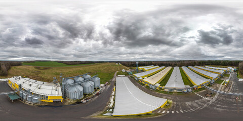 aerial seamless 360 hdri panorama view among rows of agro farms with silos and agro-industrial...