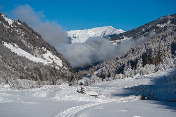 Fototapeta na wymiar a snowed in mountain road in the snow capped alps at a sunny winter day