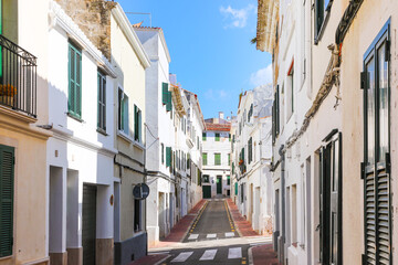 Fototapeta na wymiar A narrow street of white houses in the city of Mahón (Maó), on the island of Menorca (Balearic Islands, Spain).