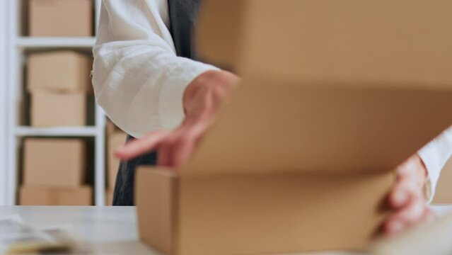 Packing goods in a cardboard box, close-up packaging process. A girl packs an item in a cardboard box to be sent to a buyer who has placed an online order in an online store
