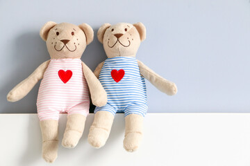 A couple of his and hers teddy bear in light pink and blue striped clothing with red heart pattern,...