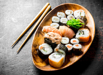 Assortment of different types of sushi, rolls and maki on a wooden plate.