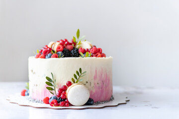 Fashionable cake from pastry chef on white background. Beautiful dessert decorated with berries with macaroons cake. Cake for holiday