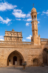Viev of Anitli virgin mary Monastery of Mardin Province, beautiful stone architecture tower with cross stairs wall and door with blue sky with clouds