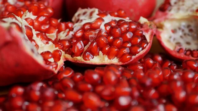 Close-up of ripe juicy red pomegranates broken into pieces in a dolly shot. Pomegranate juice and nectar are good for the body.