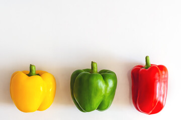 three multi-colored paprikas on a white background copyspace