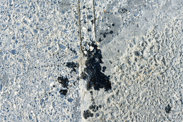 black gray spots of motor oil on an asphalt road, close-up from a parking lot, asphalt oil pollution