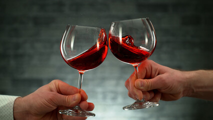 Two men clinking with glasses of red wine, celebrating success.