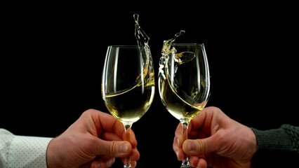Two men clinking with glasses of white wine, celebrating success.