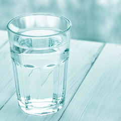 A glass of pure water stands on a white wooden background