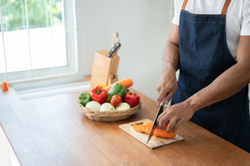 Obraz na płótnie Canvas Happy asian man preparing vegetable salad in kitchen.