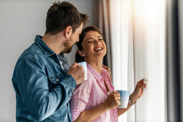 Couple in love in new home ,drinking coffee near window