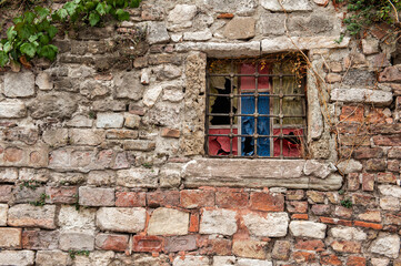 Grunge wall background with stones texture, old window and green plants