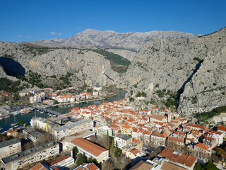 Obraz premium Aerial drone view of Omis town in Croatia. Location is where the Cetina River meets the Adriatic Sea. Beautiful city next to the mountains and the sea. Travel and holidays destination.