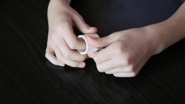 The girl unrolls a part of the adhesive tape and cuts off the required length.